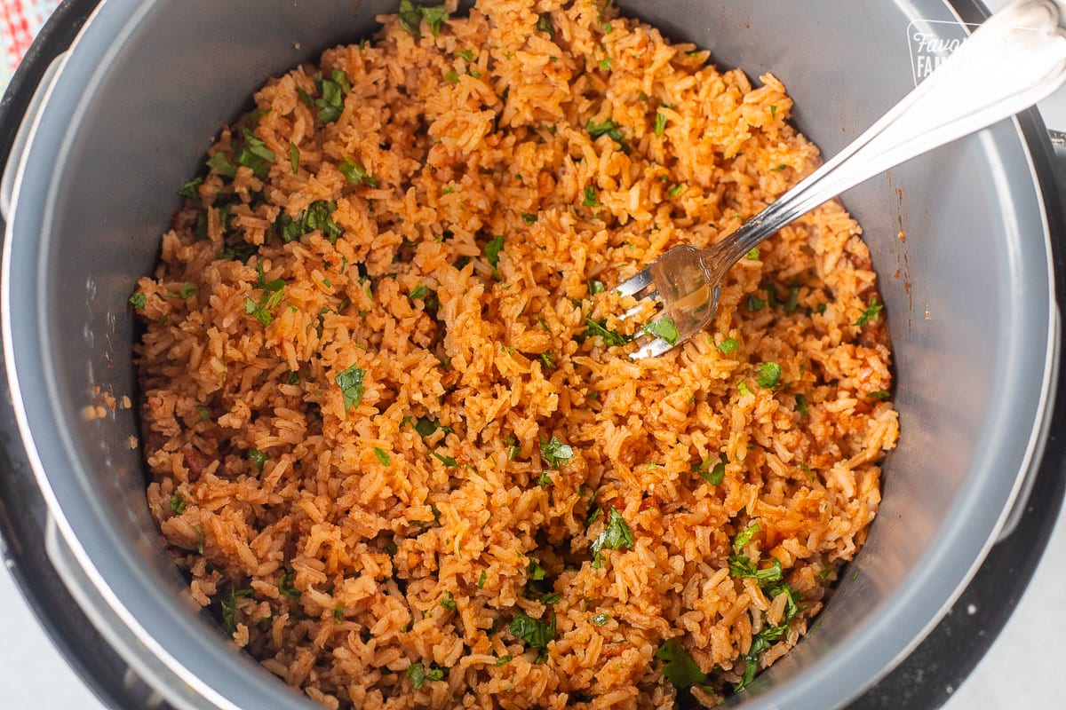 Mexican rice in an instant pot with a fork and fresh cilantro.