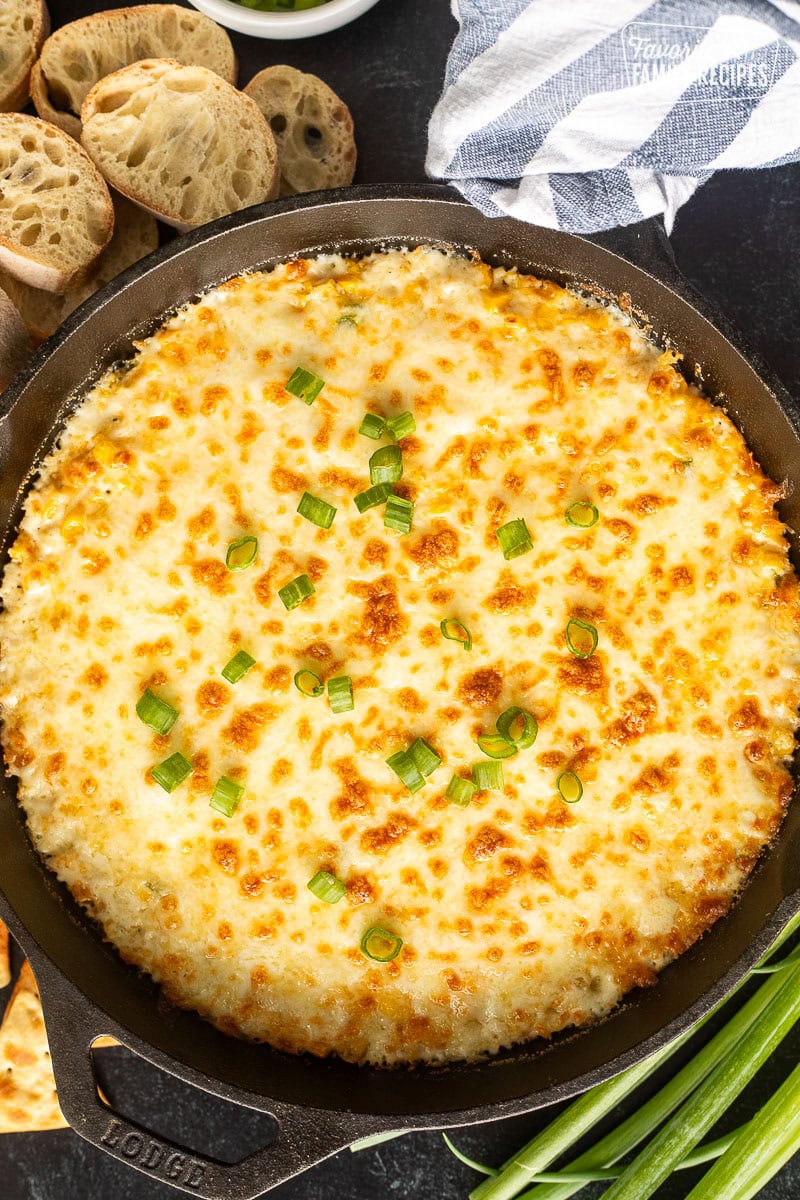 Baked Corn Cheese in a skillet and topped with sliced green onions.