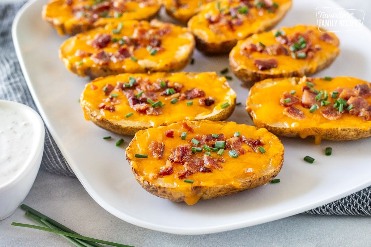 Side of loaded potato skins on a platter with melted cheddar cheese, crispy bacon, and chives.