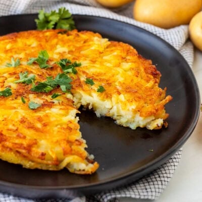 Rosti on a plate garnished with parsley and a cut out with a fork.