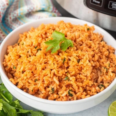 Instant pot Mexican rice in a bowl with cilantro and fresh limes on the side.