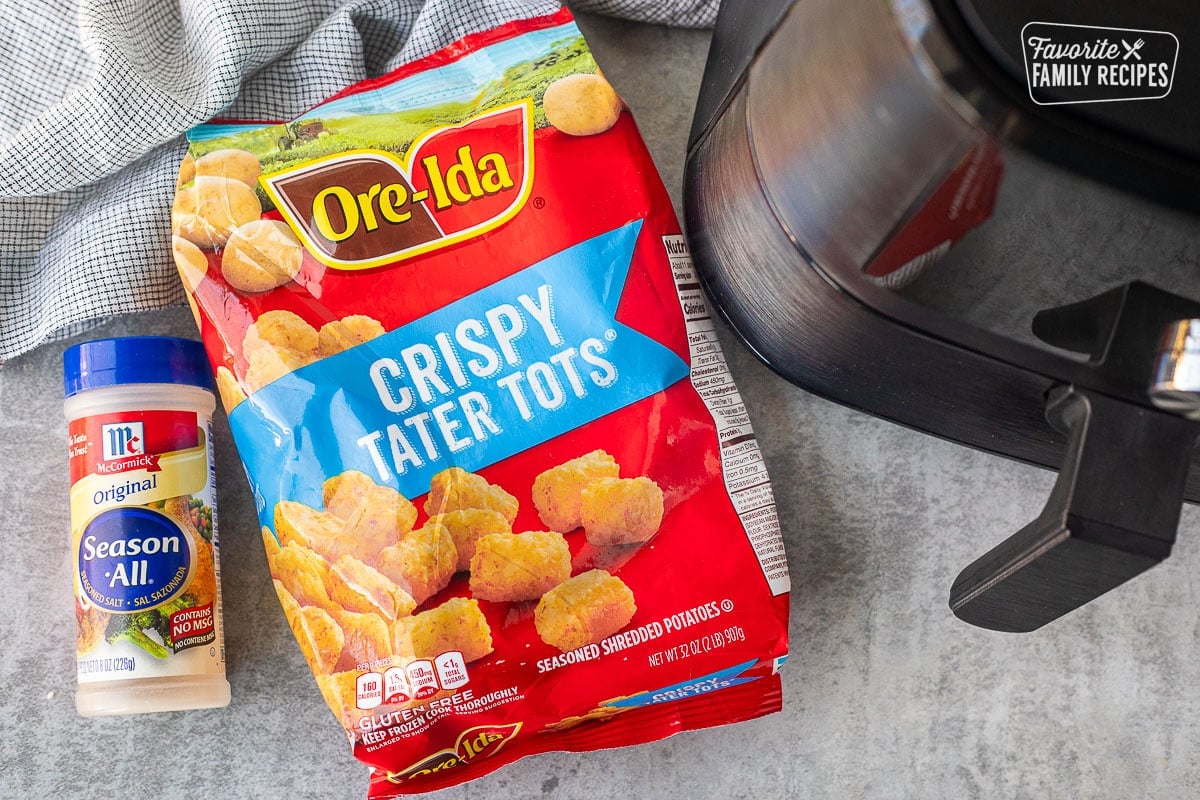 Ingredients to make Frozen Tater Tots in the Air Fryer including a bag of frozen tater tots, seasoning salt and an air fryer.