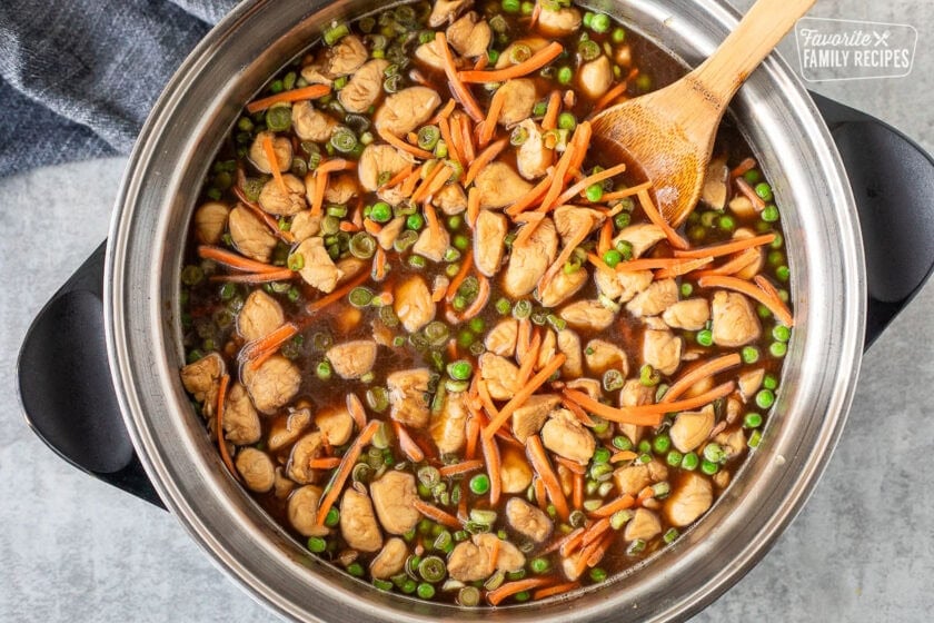 Skillet of stirred teriyaki chicken with uncooked rice.