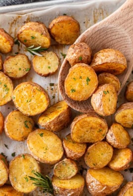 Roasted red potatoes on a baking dish with a wooden spoon.