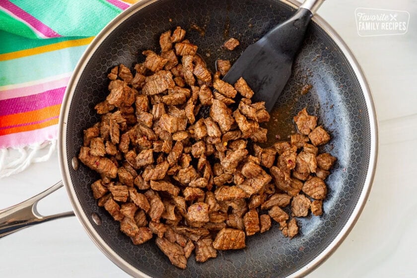 Skillet with cut up, seasoned and cooked carne asada.