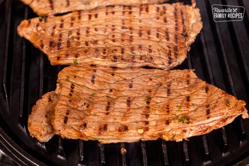 This slices of beef for carne asada cooking on grill.