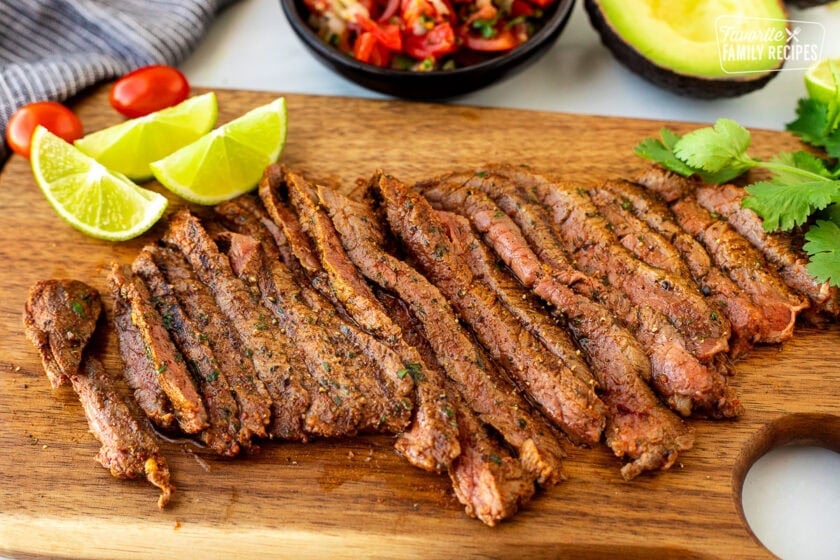 Grilled Carne Asada meat seasoned and sliced on a cutting board.