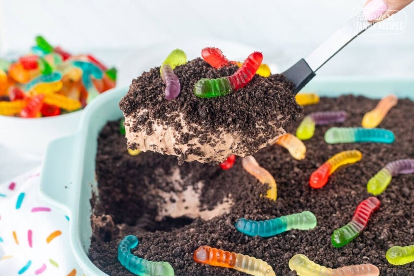 Scoop of dirt cake with gummy worms and a large spoon.