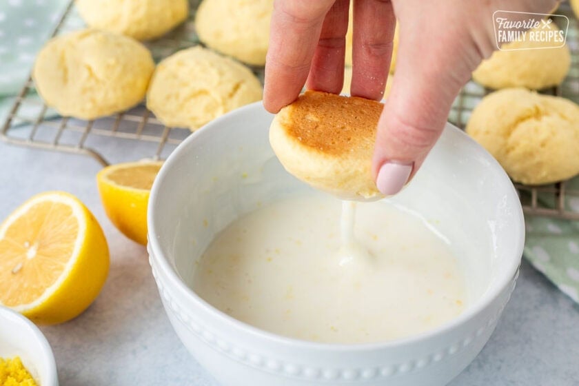 Dipping Italian lemon cookies into a bowl of lemon icing.