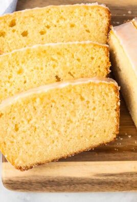 Cutting board with slices of lemon pound cake surrounded by fresh lemons.