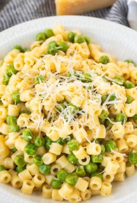 Pasta with peas in a small bowl with fresh grated cheese and pepper.