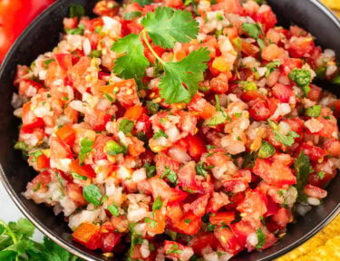 Bowl of fresh pico de Gallo with diced tomatoes, onions, cilantro and jalapeño. Garnished with fresh cilantro.