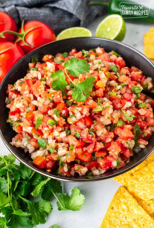 Bowl of fresh pico de Gallo with diced tomatoes, onions, cilantro and jalapeรฑo. Garnished with fresh cilantro.