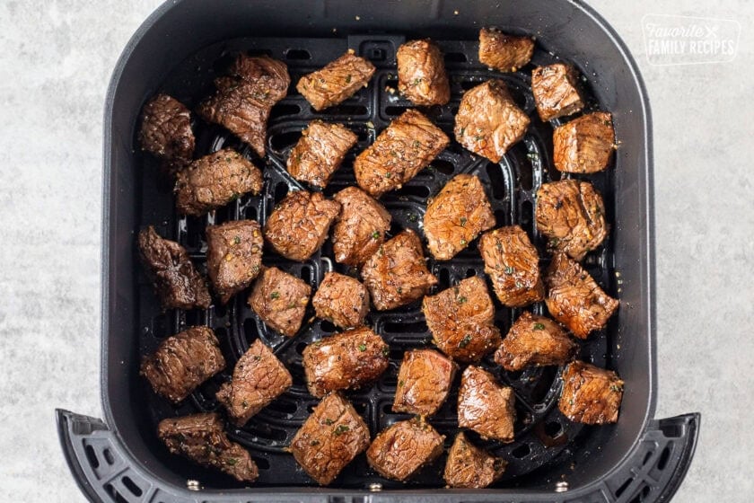 Air fryer with cooked steak bites.
