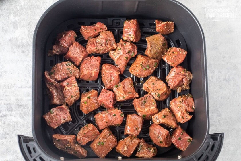 Air fryer with seasoned cut steak bites.