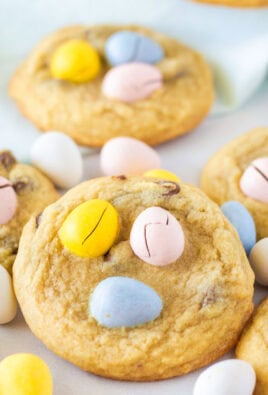 Close-up of golden brown Easter egg cookies with pink, blue, yellow, and white Cadbury Mini Eggs on top.