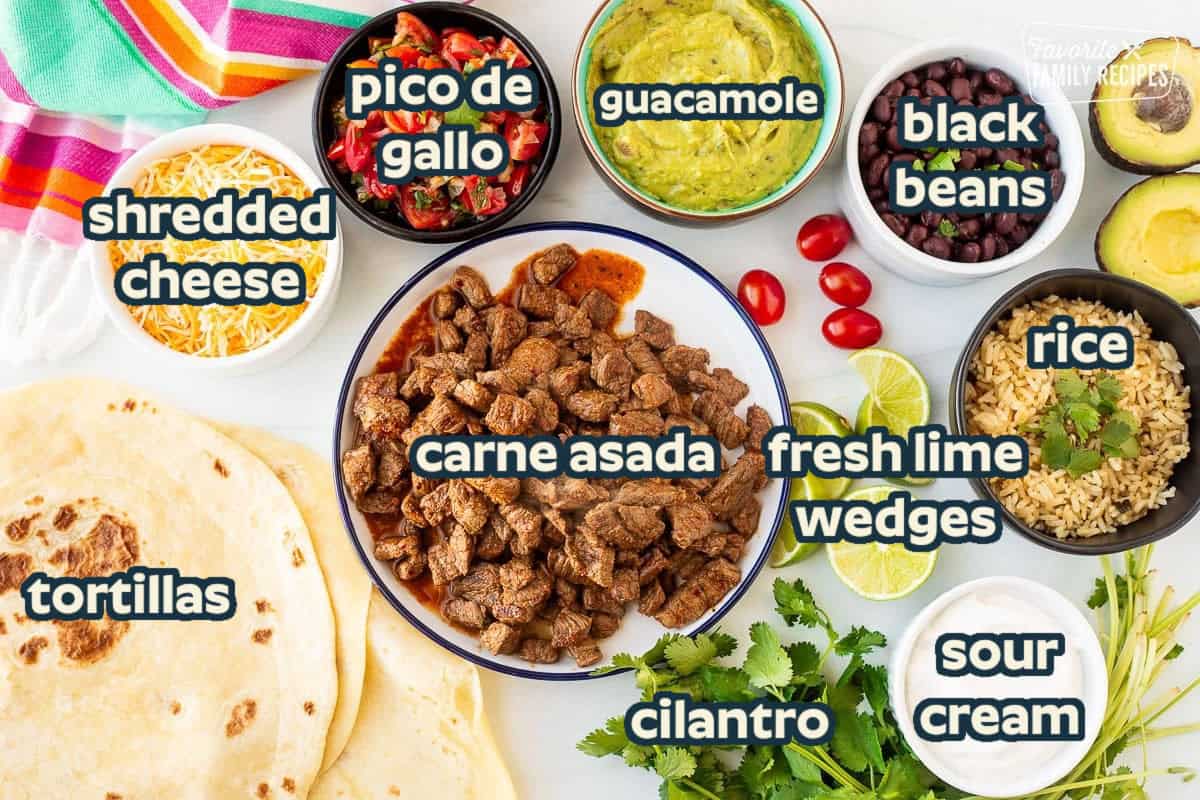 Ingredients to make a Carne Asada Burrito including carne asada, cilantro, sour cream, rice, avocado, guacamole, black beans, pico de gallo, tortillas and shredded cheese.