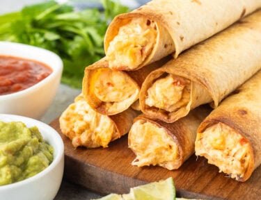 Chicken flautas stack together with a side of guacamole and salsa.