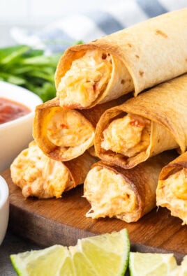 Chicken flautas stack together with a side of guacamole, lime wedges and salsa.