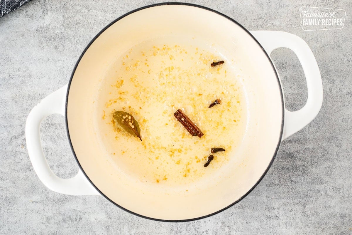 Skillet of browned garlic with cinnamon, cloves and bay leaf.