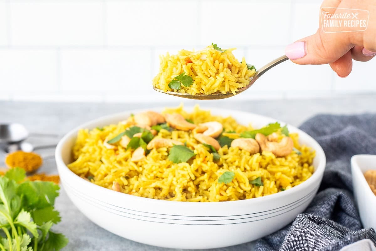Spoonful of coconut rice held over a bowl.