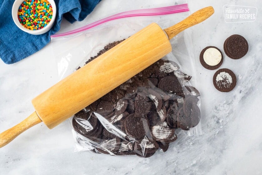 Ziplock bag with Oreos missing filling and rolling pin to crush them from the outside of the bag.