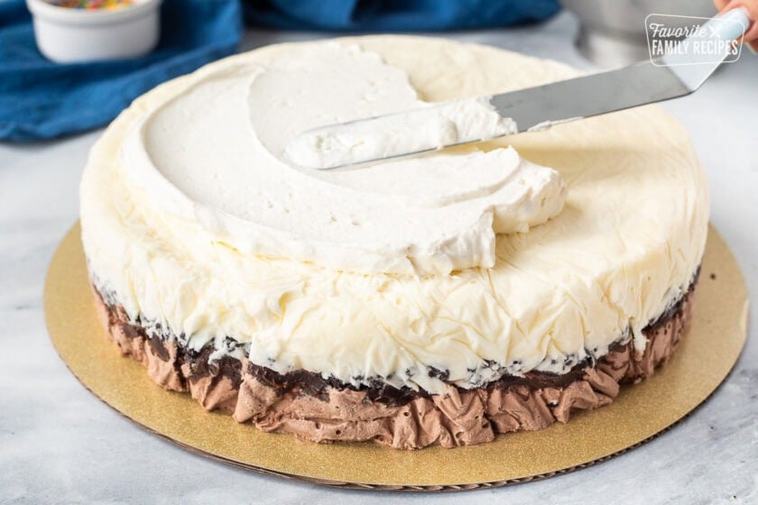 Spreading stabilized whipped cream onto frozen ice cream cake.