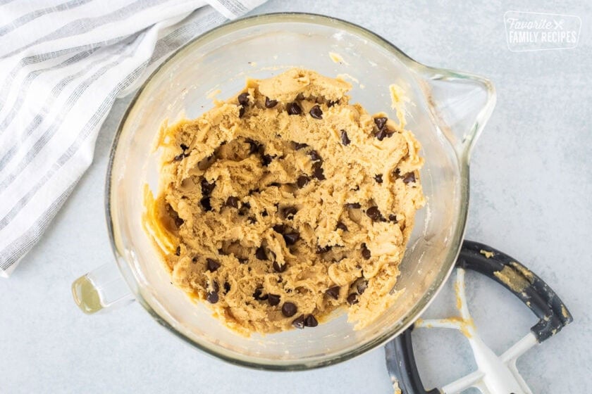 Glass mixing bowl with chocolate chip pizookie dough. Paddle attachment on the side.