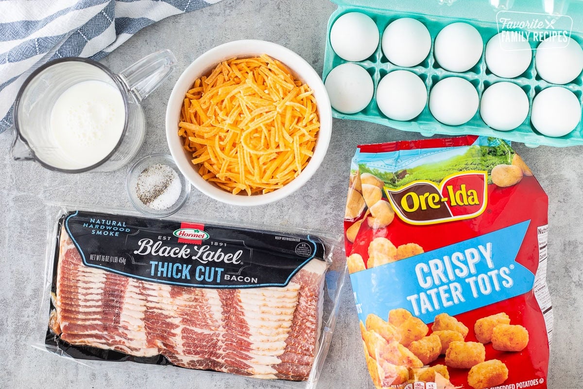 Ingredients to make tater tot breakfast casserole including eggs, cheddar cheese, tater tots, thick cut bacon, salt and pepper and milk.