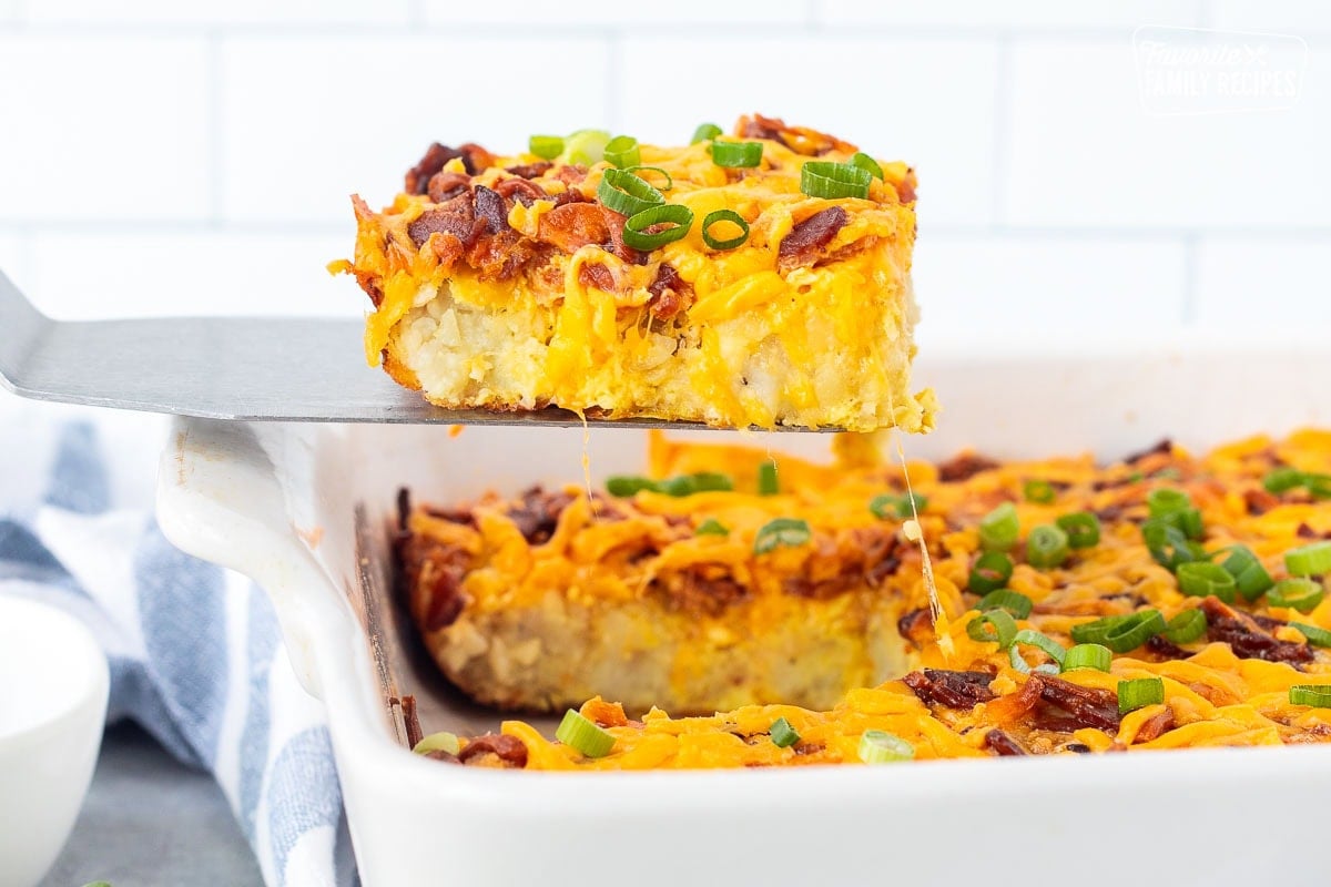 Slice of tater tot breakfast casserole on a spatula coming out of the baking dish.