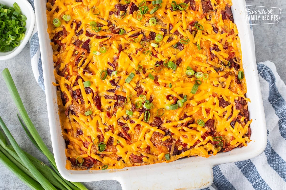 Tater tot breakfast casserole with tater tots, cheddar cheese, bacon and garnished with green onions.