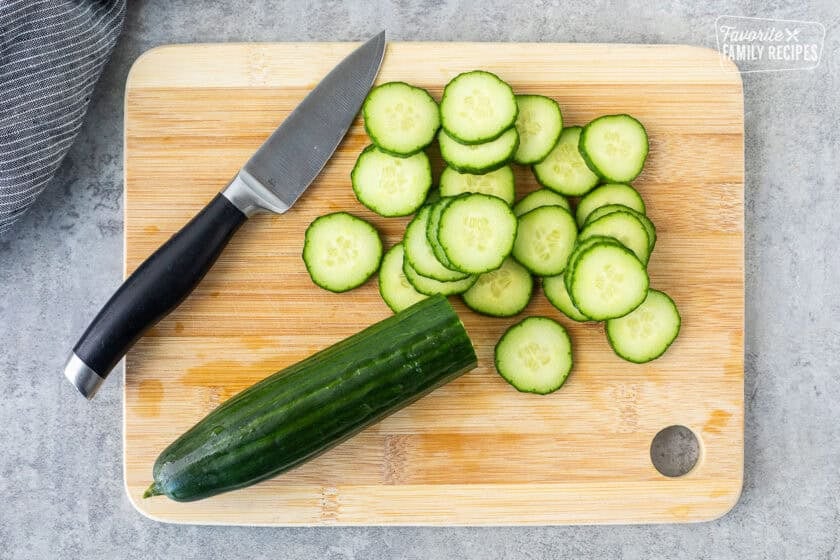 Sliced English cucumber on a cutting board with a knife.