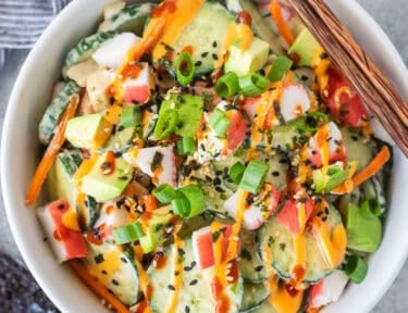 California Roll Cucumber Salad with sliced cucumbers, cut imitation crab, avocados, carrot, green onion, spicy mayo and sriracha.