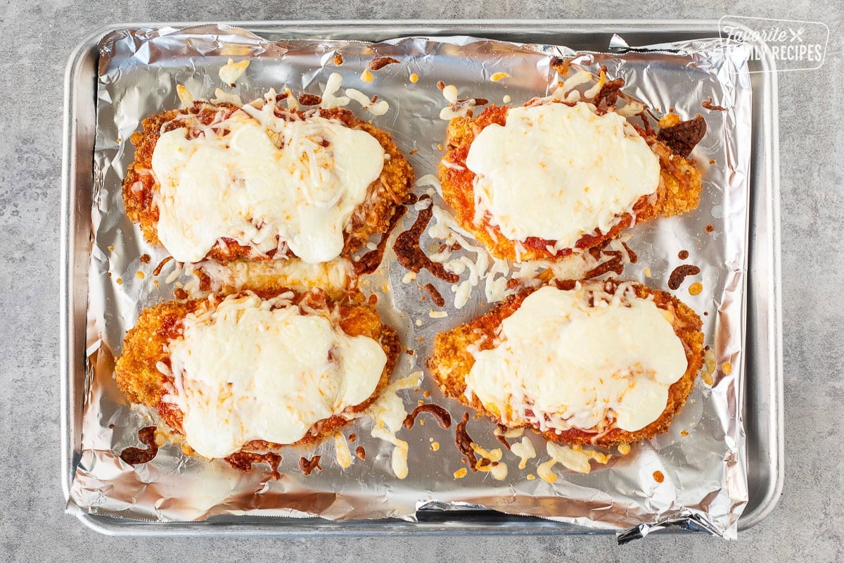 Chicken Parmesan on a baking sheet with melted mozzarella cheese.