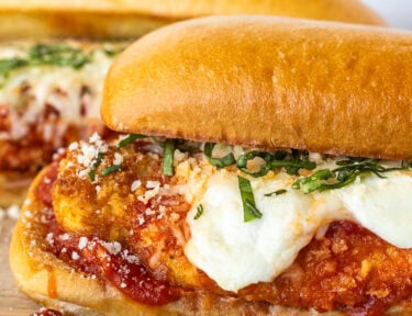 Chicken Parmesan Sandwiches with marinara, melted mozzarella cheeses and fresh basil for garnish.