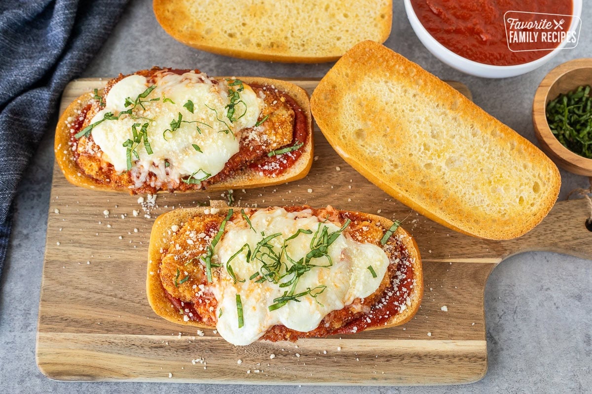 Chicken Parmesan Sandwiches with marinara, melted mozzarella cheeses and fresh basil for garnish.