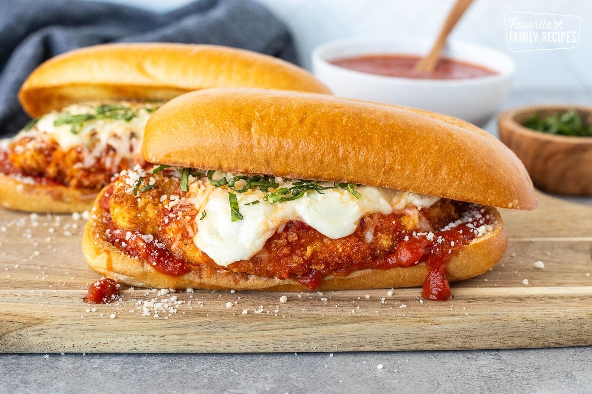 Chicken Parmesan Sandwiches with marinara, melted mozzarella cheeses and fresh basil for garnish.