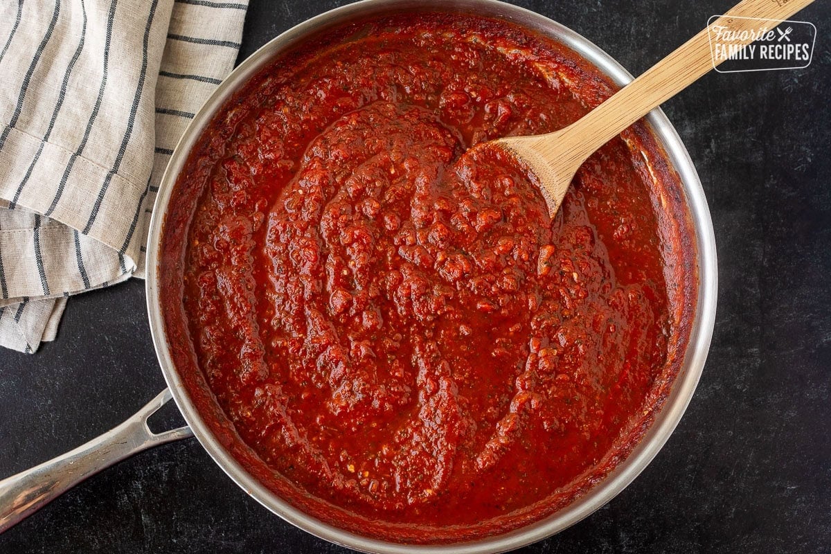 Marinara sauce in a skillet with a wooden spoon.