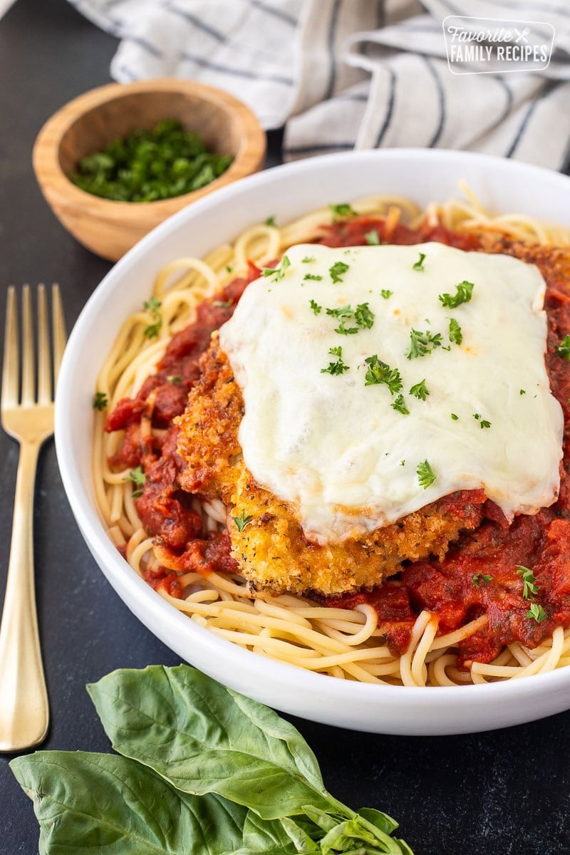 Chicken Parmesan with homemade marinara sauce, spaghetti noodles, melted mozzarella cheese and parsley.