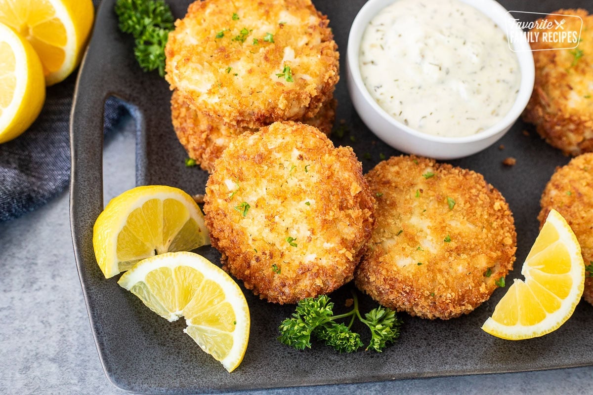Crab cakes on a plate with a small bowl of tartar sauce.