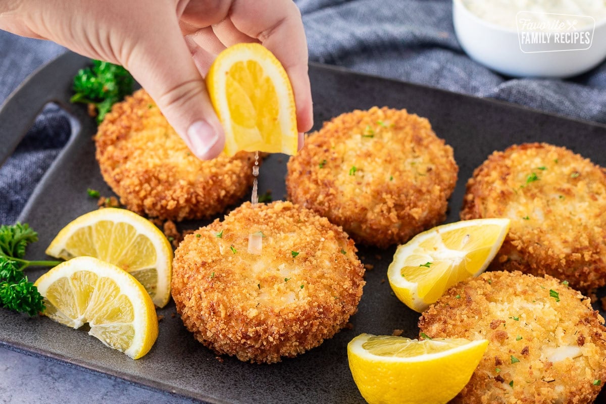 Squeezing a lemon onto a golden crab cake.