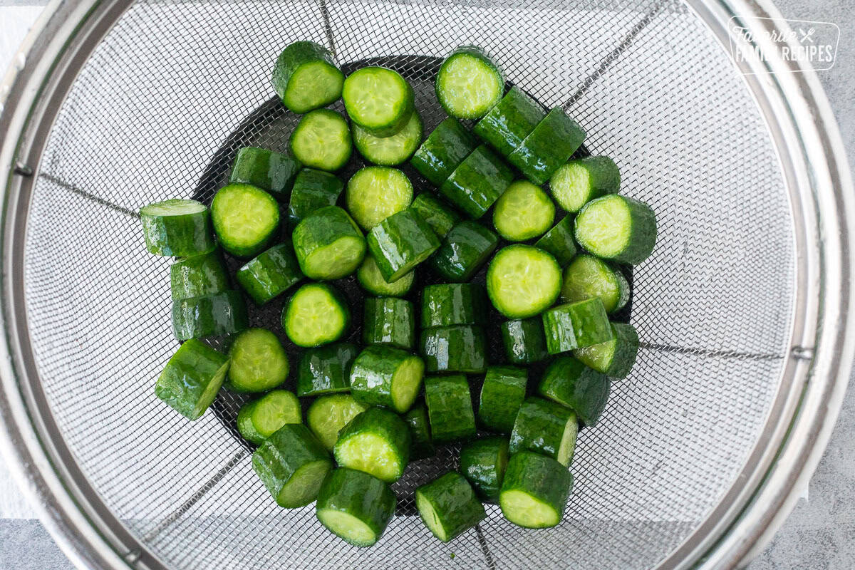 Rinsed and drained cut baby cucumbers in a colander.