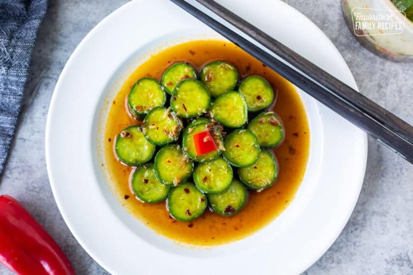 Din Tai Fung Cucumber Salad on a plate with a small cut Fresno pepper on top. Chop sticks resting on the plate.