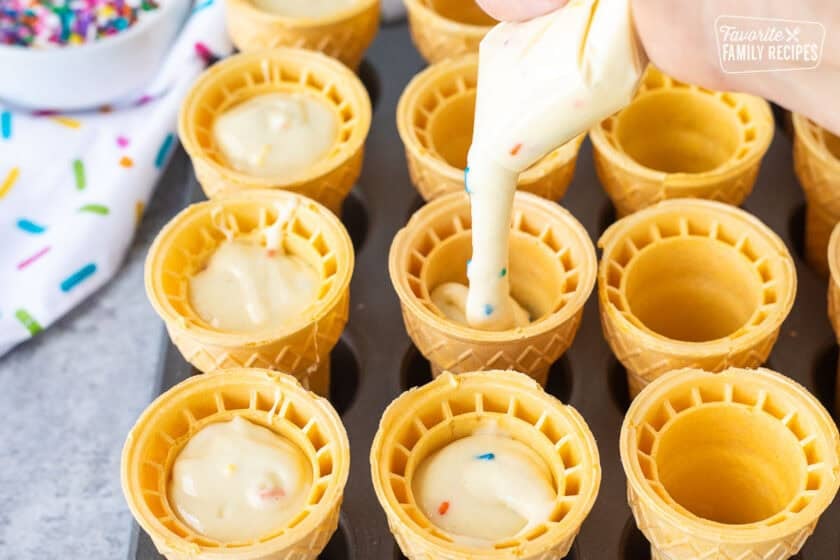 Piping cake batter into ice cream cones.