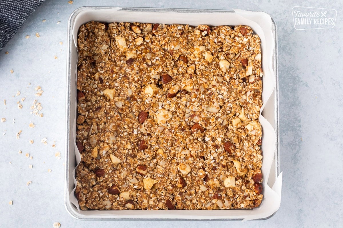 Peanut Butter Granola Bars pressed down in a bar pan lined with parchment paper.