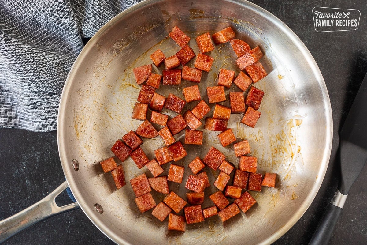 Fried spam cubes in a skillet with teriyaki sauce.