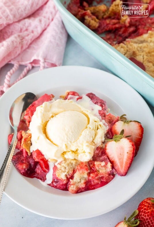 Strawberry Cheesecake Dump Cake on a plate topped with vanilla ice cream.