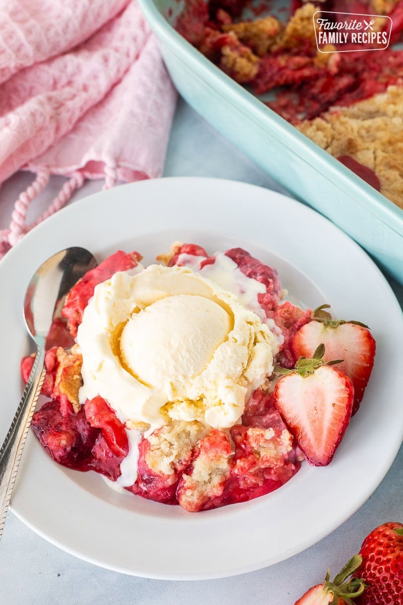 Strawberry Cheesecake Dump Cake on a plate topped with vanilla ice cream.