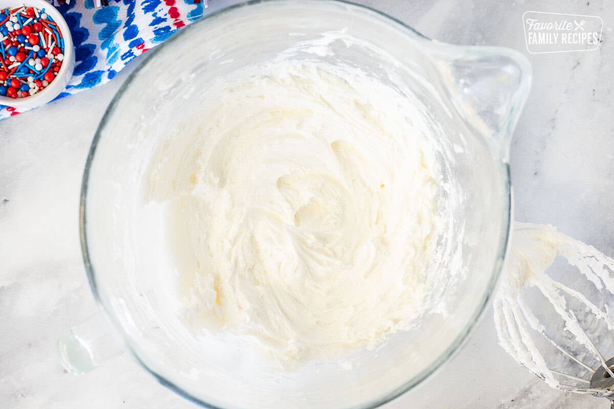 Glass mixing bowl with white cupcake frosting.