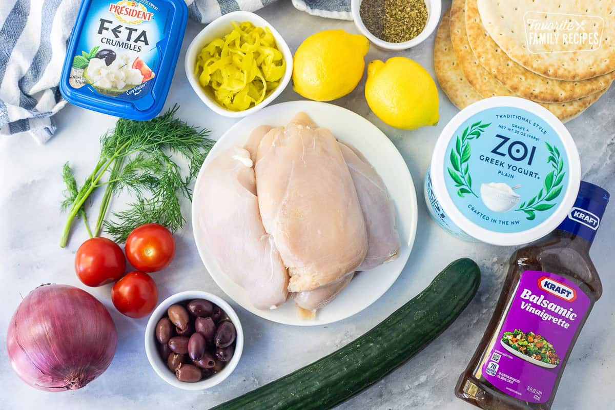 Ingredients to make Chicken Gyros including pita bread, seasonings, greek yogurt, balsamic vinaigrette dressing, cucumber, chicken breasts, lemons, greek peppers, Kalamata olives, tomatoes, dill, red onion and feta.